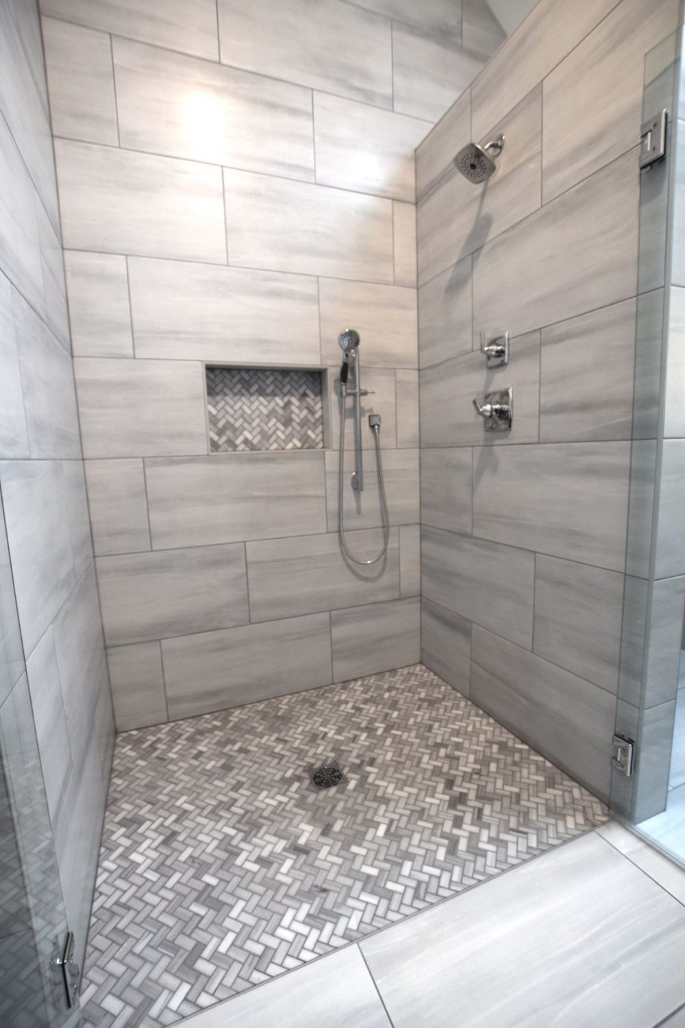 Herringbone tile shower floor with 16"X30" tile and double free swinging glass door.s.